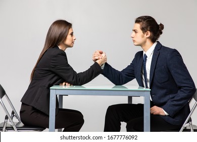 Business couple are fighting in their arms, arm wrestling between male and female. Family quarrel, showdown, division of property, divorce.