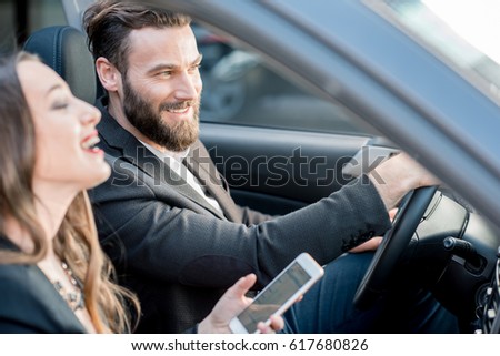 Business couple having funny conversation while driving a car in the city