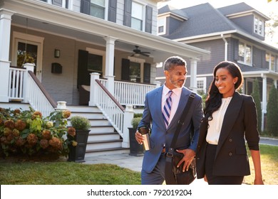 Business Couple Leaving Suburban House For Commute To Work