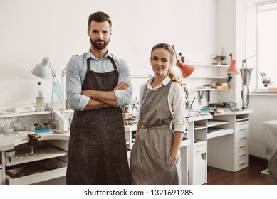 Business for a couple. Portrait of smiling couple in aprons standing at their jewelry workshop and looking at camera - Powered by Shutterstock