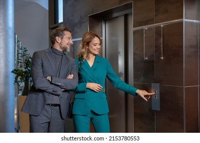 Business Couple In Suit Talking In Front Of The Elevator Door, Woman Calling Elevator