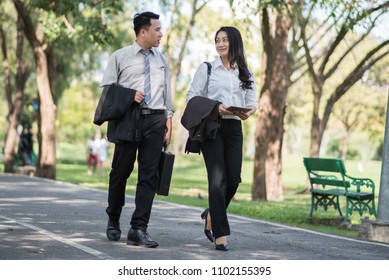 Business Couple Talking Outdoors And Walking In A Park