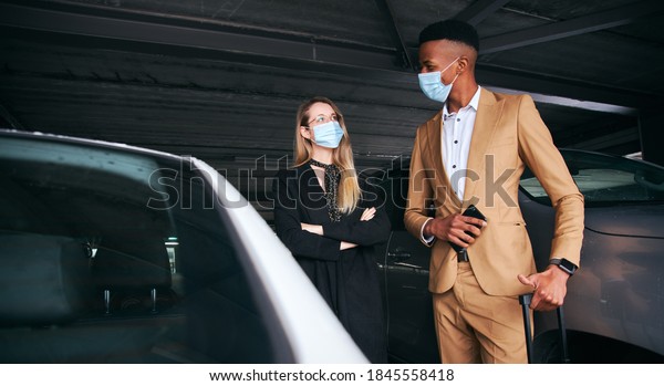 Business Couple Wearing Masks In Airport Car\
Park During Health\
Pandemic