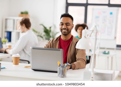 Business And Creative People Concept - Happy Smiling Young Indian Man With Laptop Computer Working At Office