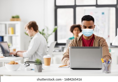 Business And Creative People Concept - Young Indian Man With Laptop Computer Wearing Protective Medical Mask For Protection From Virus Disease Working At Office