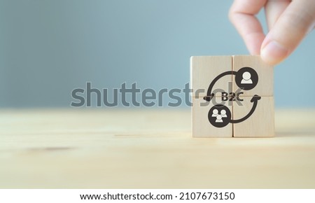 Business to customer, B2C, BTC marketing concept. Hand hold the wooden cubes with the abbreviation B2C and icon on grey background and copy space. Business, financial and marketing model concept. 