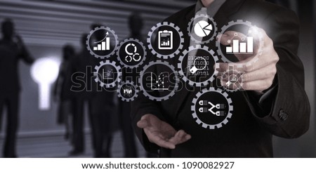 Business data analytics management with connected gear cogs with KPI financial charts and graph.Businessman hand pressing an imaginary button on virtual screen