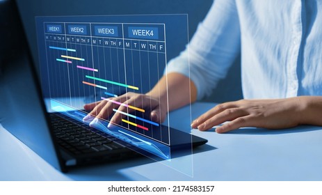 Business Data Management System. Project manager working on laptop and updating tasks and milestones progress planning with Gantt chart scheduling interface for company on virtual  screen. - Shutterstock ID 2174583157