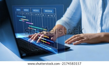 Business Data Management System. Project manager working on laptop and updating tasks and milestones progress planning with Gantt chart scheduling interface for company on virtual  screen.
