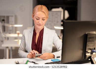 business, deadline and technology concept - businesswoman with smartphone and computer working at night office - Shutterstock ID 1213128982