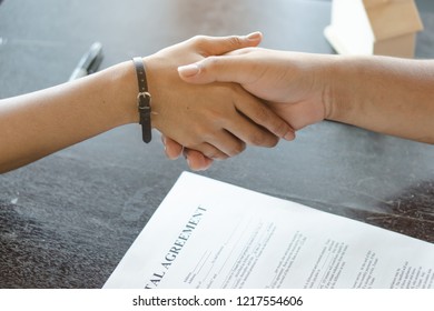 Business deal done. Above view of client handshakes with property agent after signed contract agreement rent apartment.