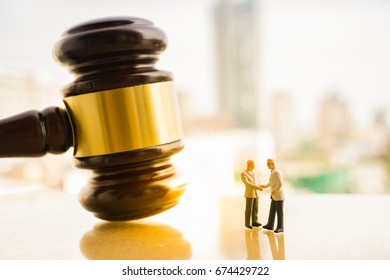 Business Deal, Legally And  Illegally Binding Contract Concept. Miniature People : Small Figures Make Handshaking Agreement With Judge Gavel Background.