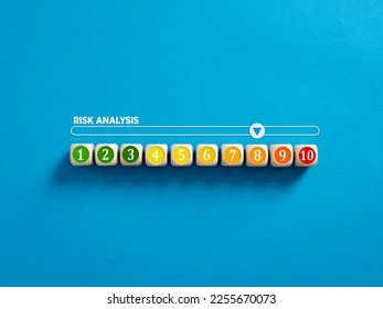 Business decision making and risk analysis. Measuring high risk. Risky business environment. Risk management. Numbers on wooden cubes with a gauge meter bar on blue background.