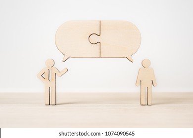 Business and design concept - group of wooden businessman icon with jigsaw dialogue frame on wooden desktop and white background.  it's discussion, leadership concept - Shutterstock ID 1074090545