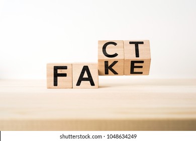 Business and design concept - surreal abstract geometric wooden cube take by hand with word " FACT & FAKE " concept on wood floor and white background