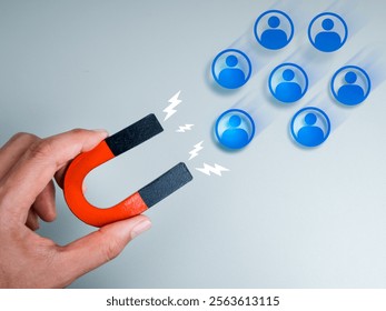 Business digital marketing, data network, attract leads and customers concept. Human people icons attracted by magnet in hand on grey background. Business team building, recruitment, hiring concept.
