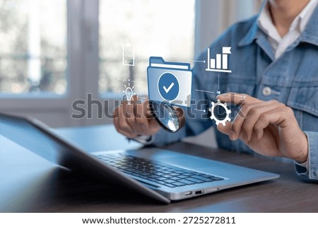 Business document verification and process management concept. Professional using magnifying glass to inspect approved digital files on laptop with workflow, quality control, and optimization icons.