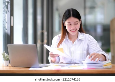 Business Documents Concept : Employee Woman Hands Working In Stacks Paper Files For Searching And Checking Unfinished Document Achieves On Folders Papers At Busy Work Desk Office. Soft Focus