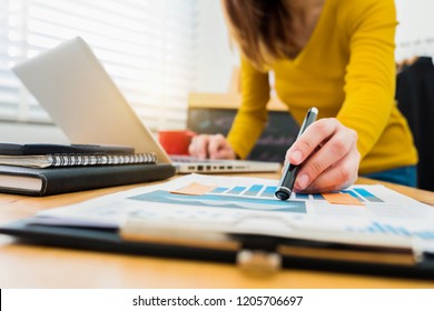 business documents on office desk with laptop and smart phone and graph business diagram and woman working at office .