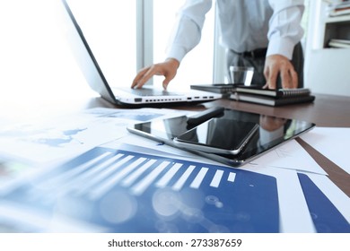 business documents on office table with smart phone and digital tablet and man working in the background