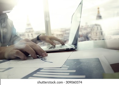 Business Documents On Office Table With Laptop Computer And Graph Financial Diagram And Man Working In The Background