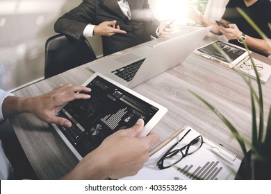 business documents on office table with smart phone and laptop computer and graph financial with social network diagram and three colleagues discussing data in the background  