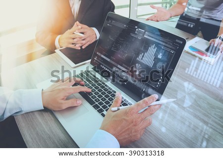 business documents on office table with smart phone and laptop computer and graph financial with social network diagram and three colleagues discussing data in the background

