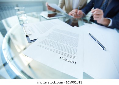 Business documents and pen at workplace with working people on background