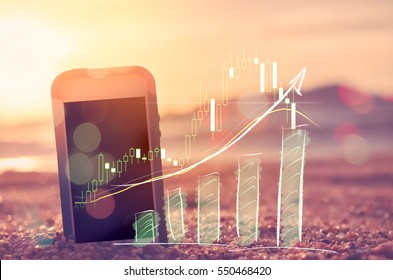 Business economic technology and freedom trader working concept. Smart phone on sand sunset beach double exposure graph money stock trading up trend arrow bar bokeh background. Vintage filter color 