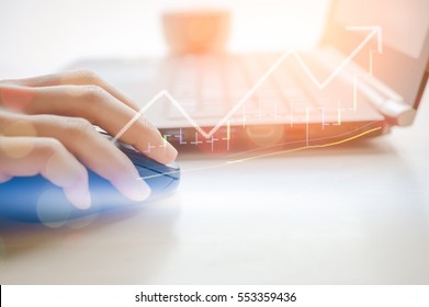 Business Economic And Technology Working Concept. Woman Hand Using Mouse Notebook Double Exposure Graph Money Stock Trading Up Trend Green Arrow Bokeh Background. Vintage Tone Filter Effect Color. 