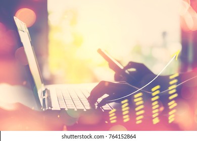 Business Economic And Technology Working Concept. Woman Hand Using Notebook Double Exposure With Graph Money Stock Trading And Blur Bokeh Light Background. Vintage Tone Filter Effect Color Style.