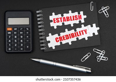 Business and Economics. On the table is a calculator, a pen and a notebook with the inscription -Establish Credibility - Shutterstock ID 2107357436