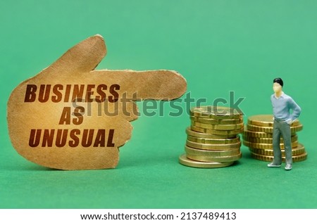 Business and economy concept. On the green surface of the coin and a figure of a man, they are indicated by a sign - a hand with the inscription - Business as unusual
