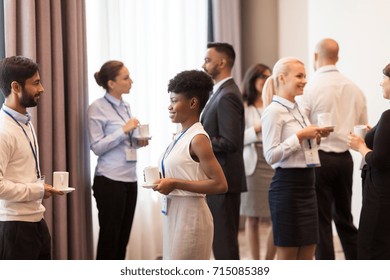business and education concept - international group of people with conference badges drinking coffee - Shutterstock ID 715085389