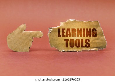 Business And Education Concept. On A Brown Surface, A Cardboard Hand Points To A Sign That Says - Learning Tools