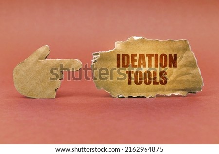Business and education concept. On a brown surface, a cardboard hand points to a sign that says - Ideation Tools