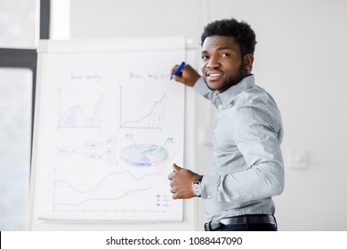 business, education and people concept - african american businessman with flip chart at office presentation