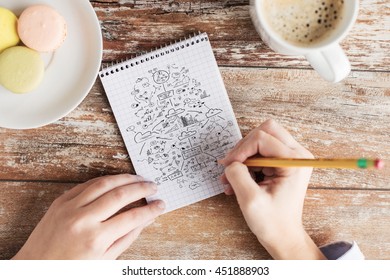 business, education, planning and people concept - close up of female hands with pencil, coffee and cookies drawing scheme to notebook on table