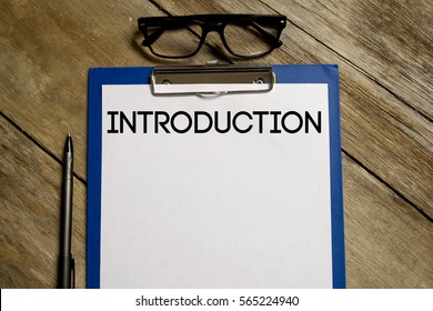 A Business And Eduction Concept.Top View Of Clipboard And White Sheet Written With INTRODUCTION On Wooden Background. A Beginning Section To A Book, Article Or Essay Which States Its Purpose And Goals