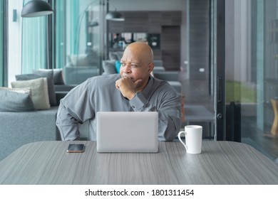 Business elderly black american man, African person working from home, thinking about problem with computer notebook laptop and suffering from depression in quarantine in corona virus pandemic concept