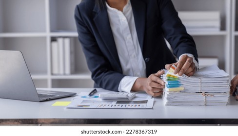 Business Employee Asian woman hand working in Stacks paper files for searching and check unfinished document archives on folders papers at busy work desk workplace office. Business Documents concept. - Powered by Shutterstock