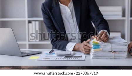 Business Employee Asian woman hand working in Stacks paper files for searching and check unfinished document archives on folders papers at busy work desk workplace office. Business Documents concept.