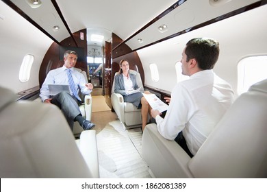 Business employees having a meeting while sitting in a private jet - Powered by Shutterstock