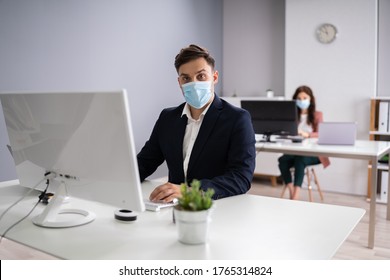 Business Employees In Office Wearing Medical Masks And Following Social Distancing Protocols