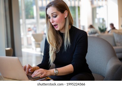 Business entrepreneur with a funny expression after receiving good news, thrilled and excited while typing on a computer