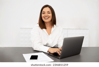 Business And Entrepreneurship Career. Cheerful Businesswoman Using Laptop, Typing Working Online And Smiling To Camera Sitting At Desk In Modern Office Interior. Employment And Successful Job - Shutterstock ID 2346811259