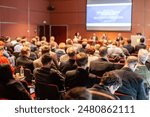 Business and entrepreneurship symposium. Speaker giving a talk at business meeting. Audience in the conference hall. Rear view of unrecognized participant in audience.