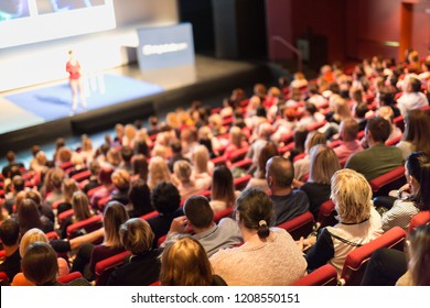 Business and entrepreneurship symposium. Speaker giving a talk at business meeting. Audience in conference hall. Rear view of unrecognized participant in audience. - Shutterstock ID 1208550151