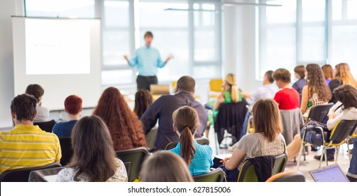 Business and entrepreneurship symposium. Speaker giving a talk at business meeting. Audience in conference hall. Rear view of unrecognized participant in audience. - Shutterstock ID 627815006