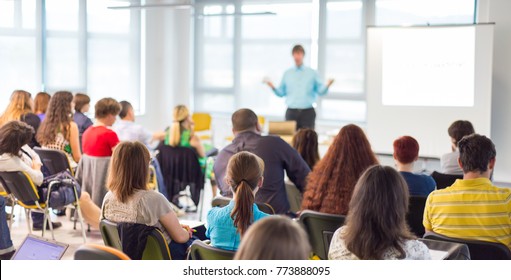 Business and entrepreneurship symposium. Speaker giving a talk at business meeting. Audience in conference hall. Rear view of unrecognized participant in audience. - Shutterstock ID 773888095